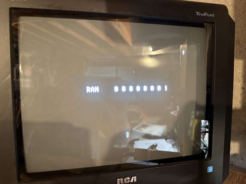 a CRT television displaying the text "RAM 0 0 0 0 0 0 0 1"