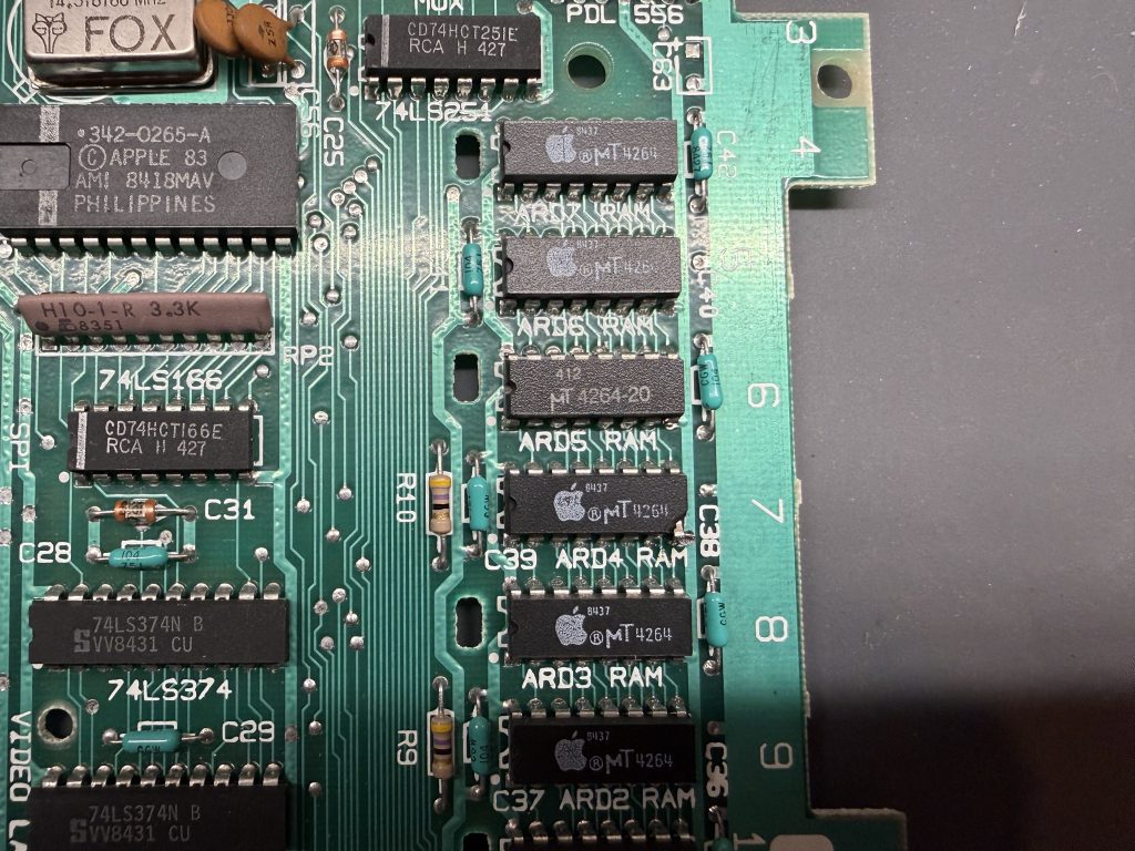 an Apple //c motherboard with a replaced RAM chip in the ARD5 position. the chip at ARD4 is damaged in one corner
