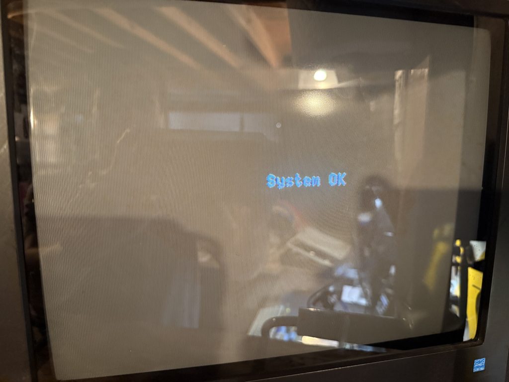 a CRT screen showing the text "System OK"