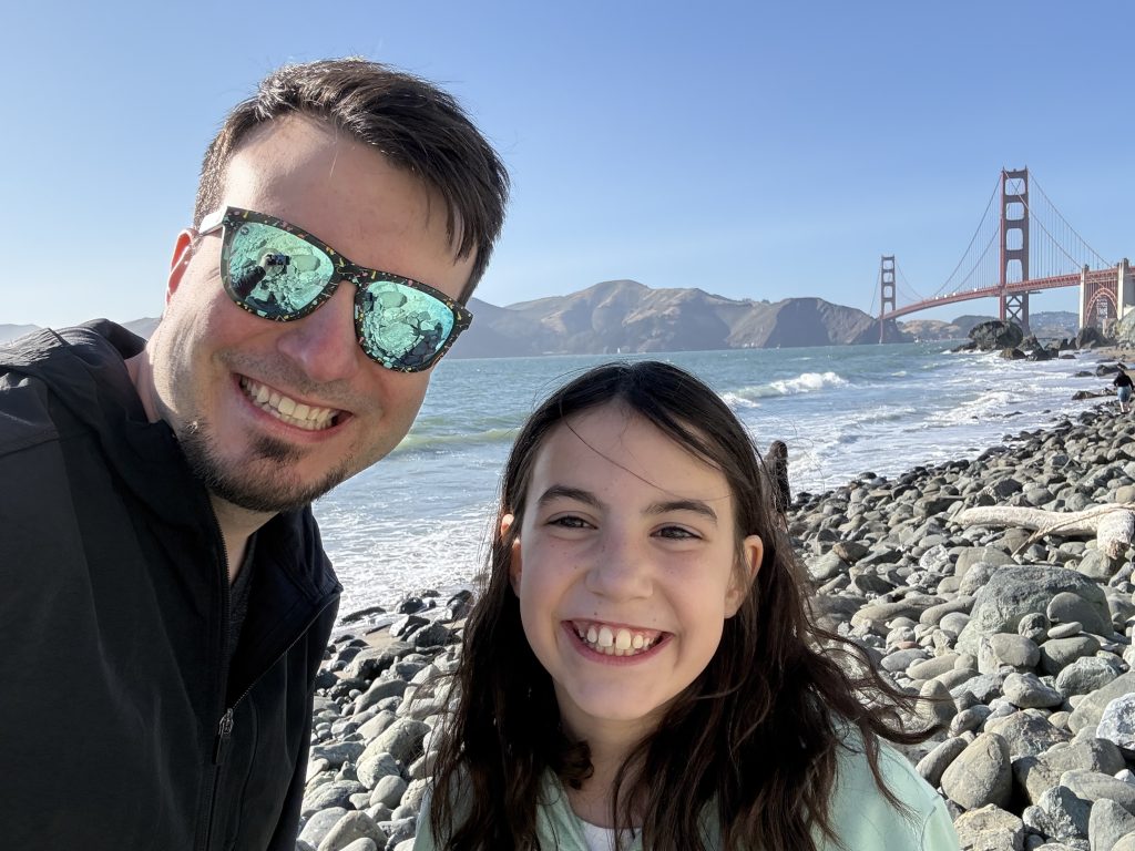 a man and girl smile in front of the golden gate bridge