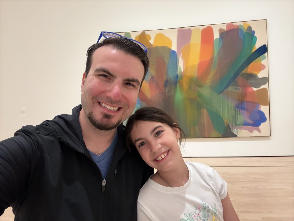 a man and young girl sit in front of colorful artwork