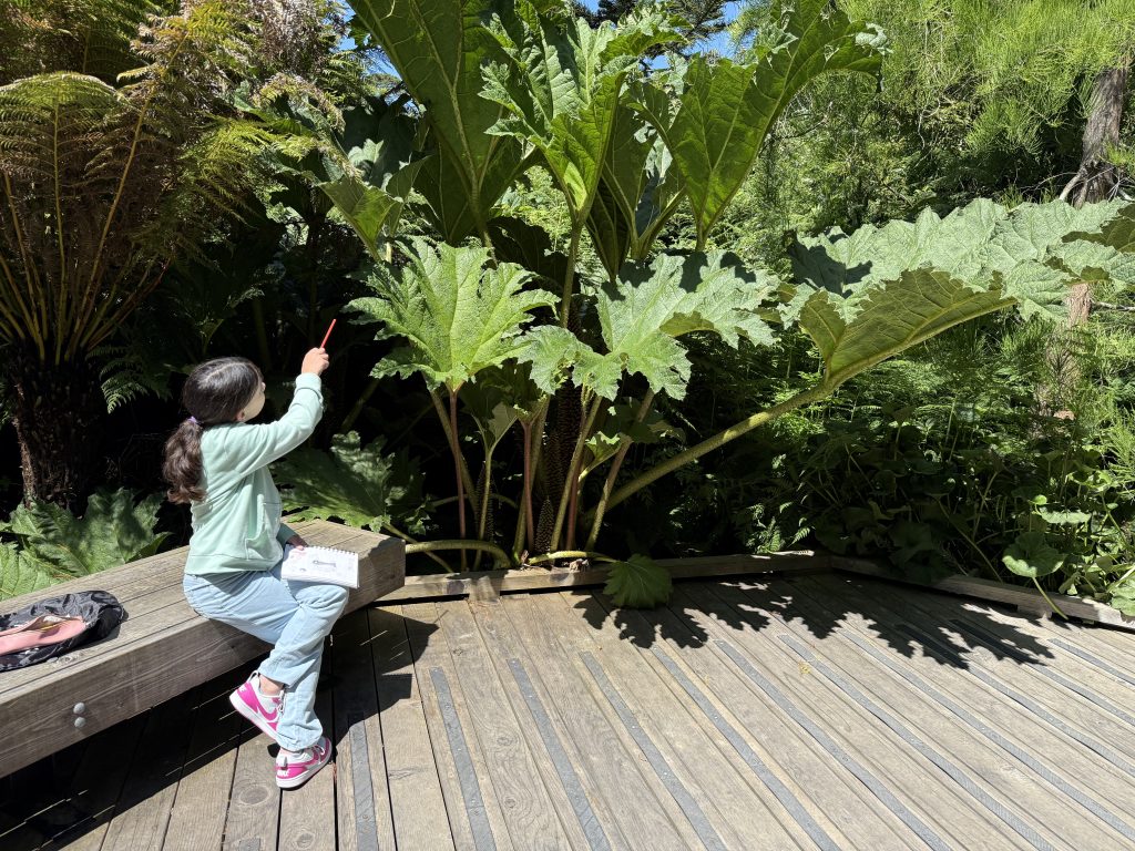 a girl sits in front of a large plant