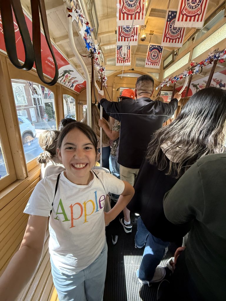 a girl stands inside a crowded cable car