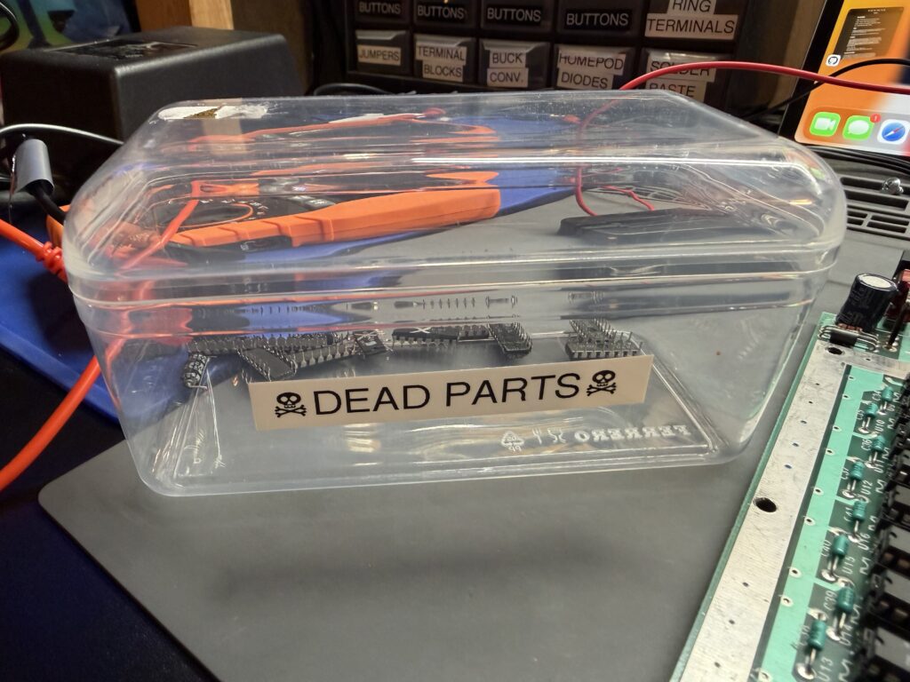 a clear plastic box with the label "Dead Parts". there are multiple chips inside