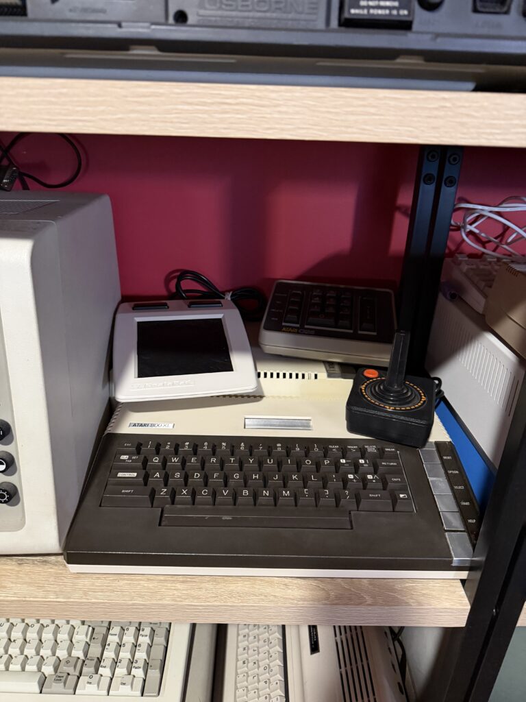 an atari 800xl sitting on a shelf next to other vintage computers